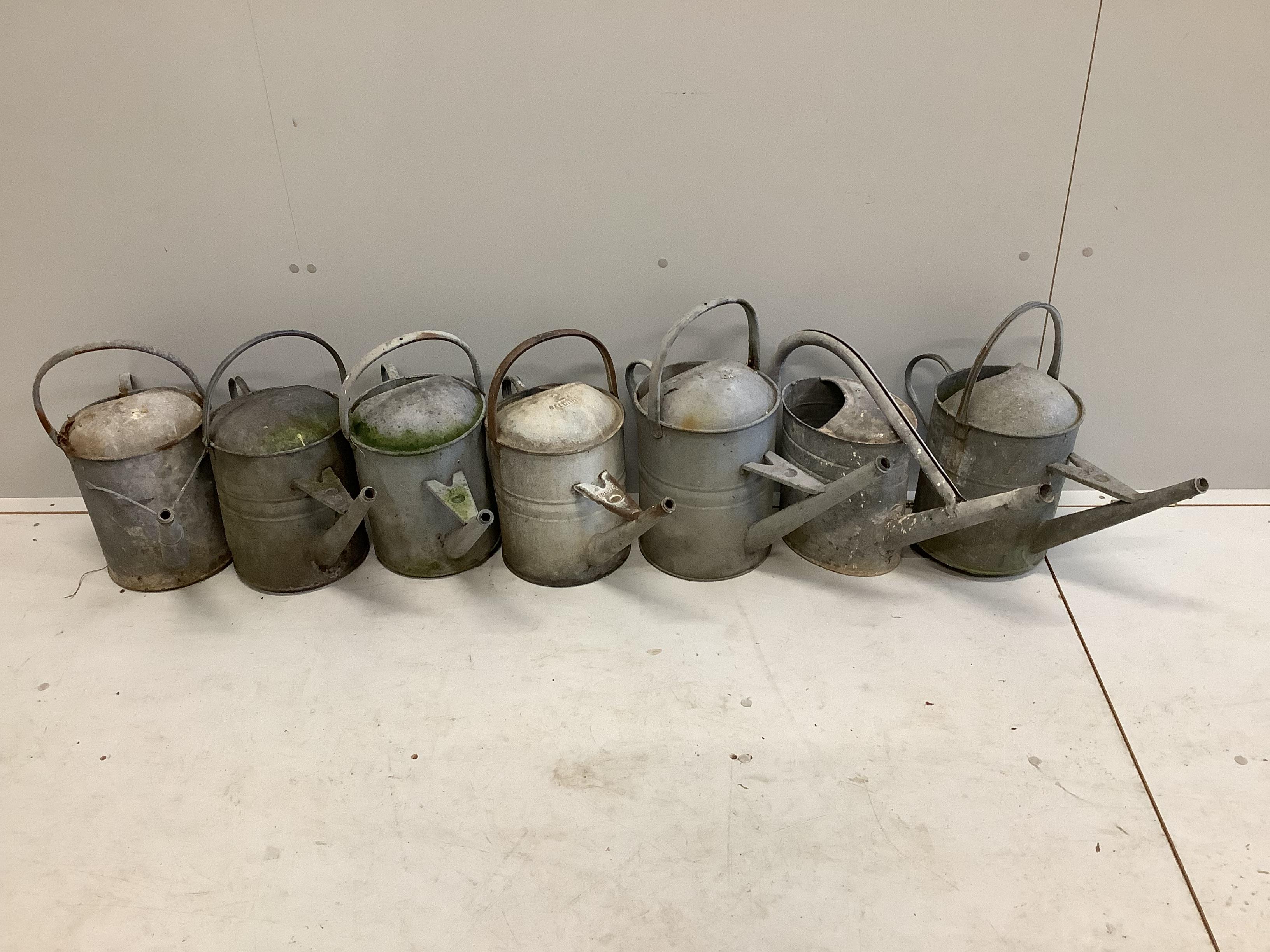 Seven vintage galvanised metal watering cans, largest height 43cm